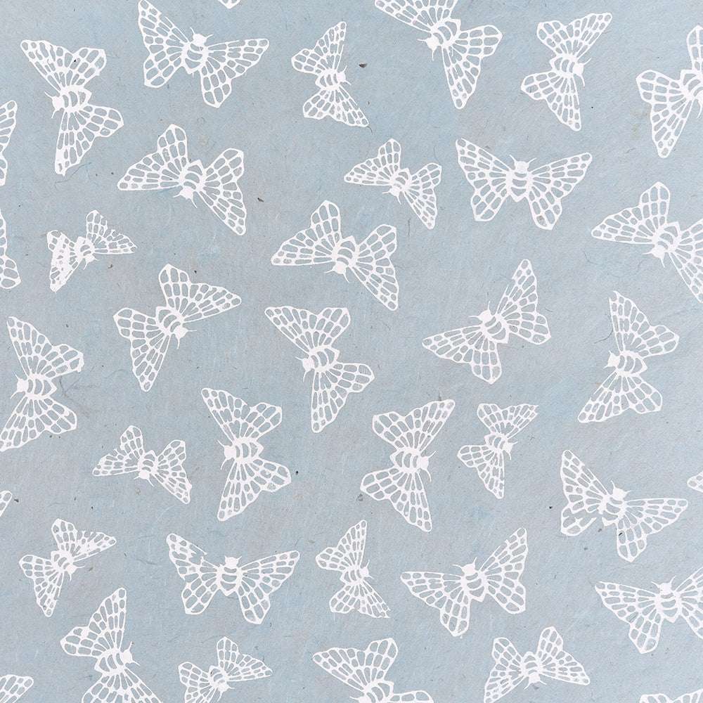 Verstreute weiße Mottenillustrationen auf hellblauem Nepalpapier von ☆, perfekt für Bastelarbeiten oder Geschenkverpackungen.