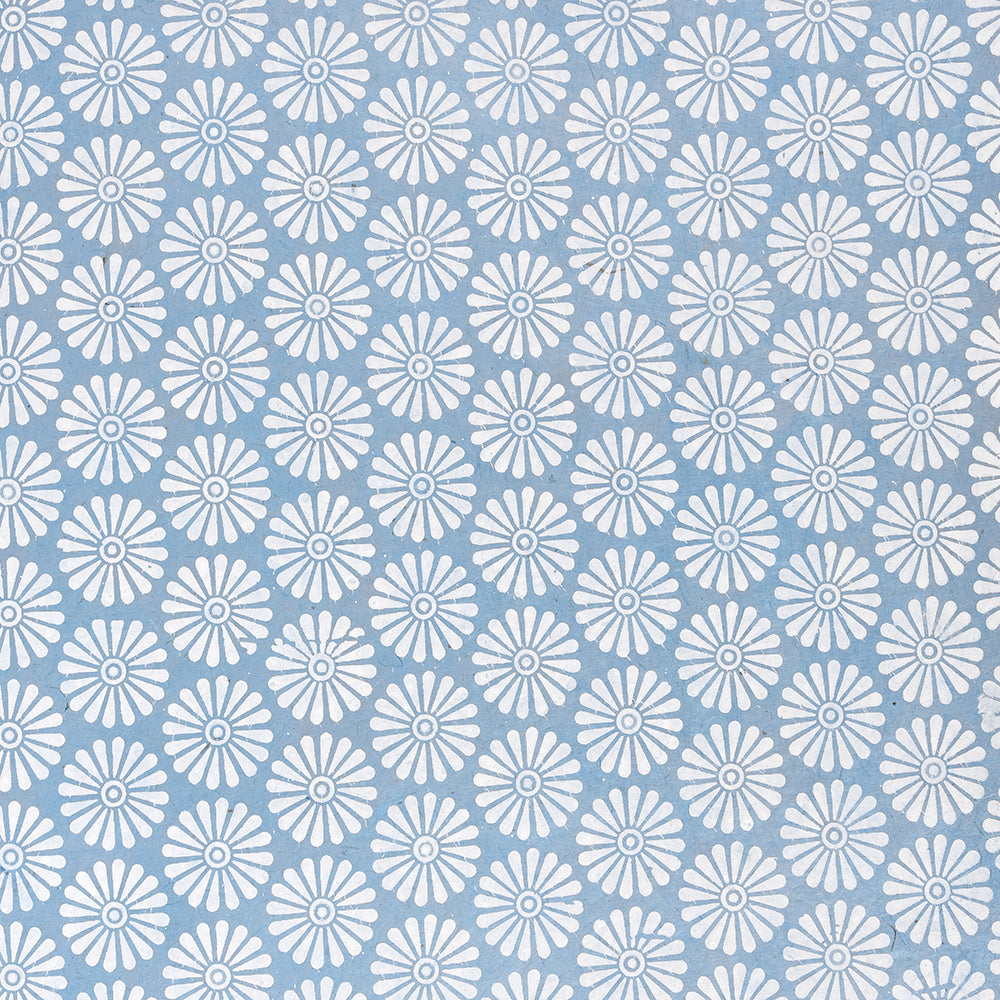 Weiße Gänseblümchen in einem sich wiederholenden Muster auf hellblauem Hintergrund, gedruckt auf nachhaltigem Papier für umweltfreundlichen Stil.