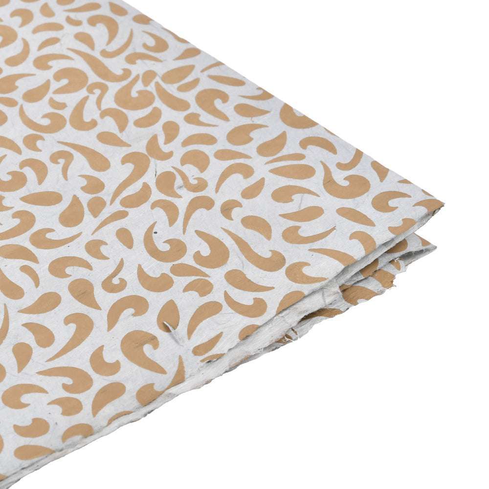 Weißes strukturiertes Nepalpapier mit eingestreutem hellbraunem Paisleymuster, an der Ecke leicht gefaltet - ideal zum Einpacken von Geschenken oder für Buchbindeprojekte.
