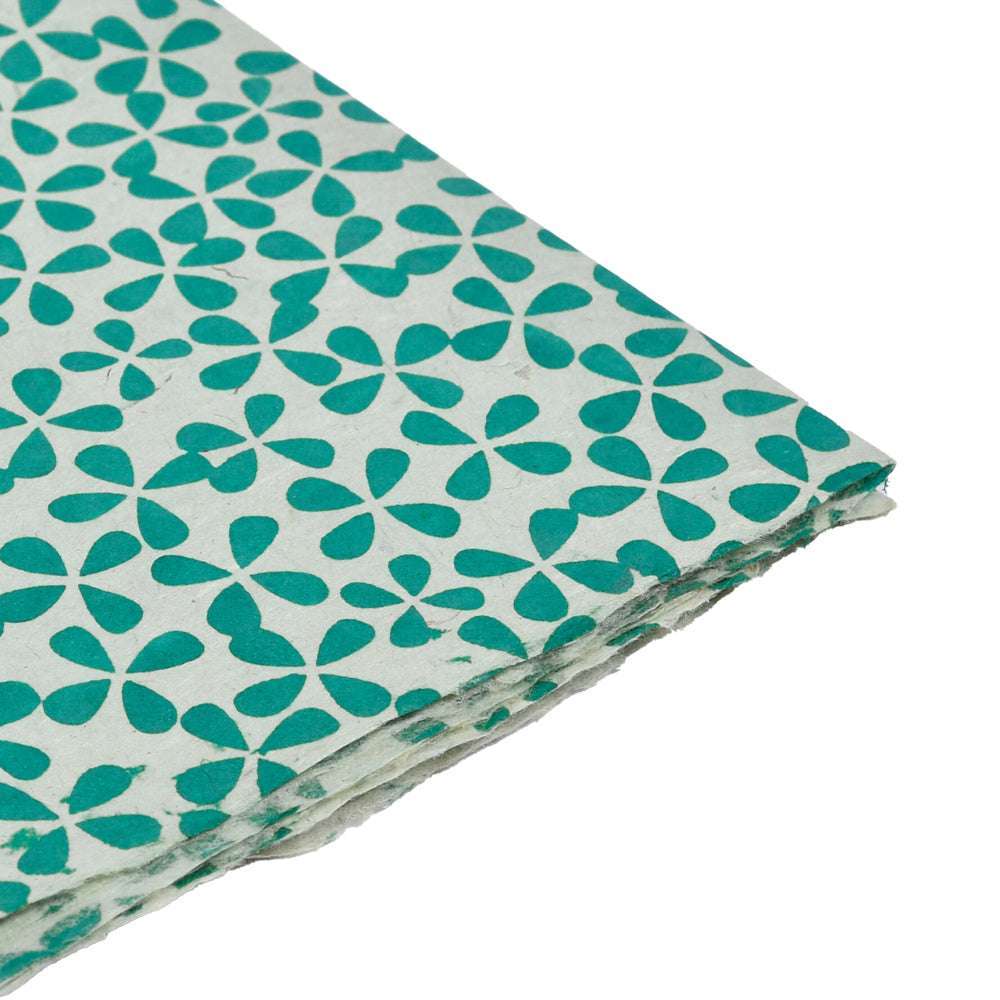 Weiße Nepalpapierbögen mit grünem, geometrischem Blütenmuster, ideal zum Verpacken von Geschenken oder zum Einbinden von Büchern, sauber gestapelt auf weißem Hintergrund.