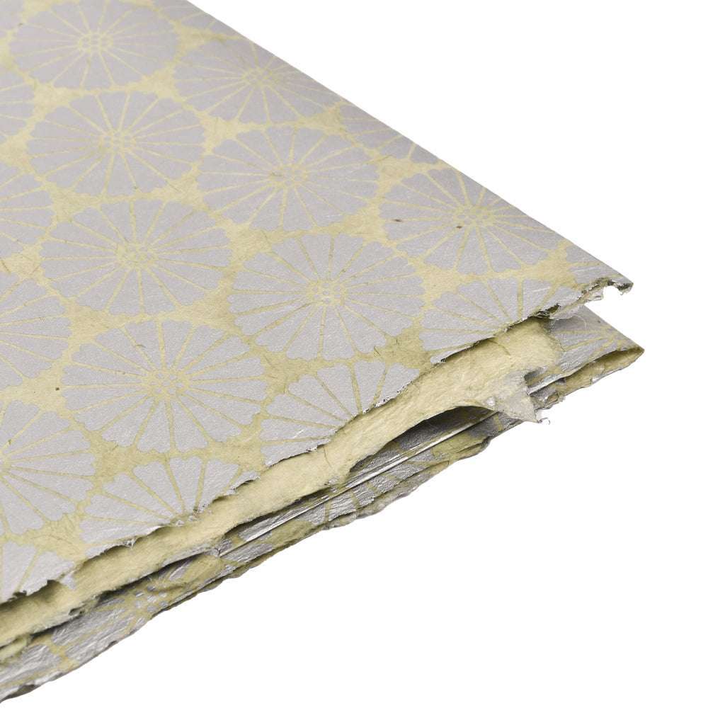 Ein Stapel ☆ strukturiertes Nepalpapier mit silbernem Blumenmuster auf hellgelbem Grund - ideal zum Verpacken von Geschenken oder zum Buchbinden.
