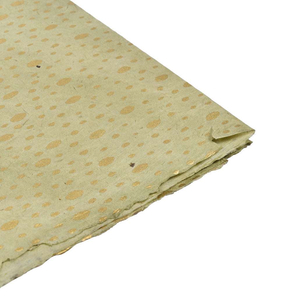 Hellgrünes handgefertigtes Nepalpapier mit goldenen Tupfen, ideal zum Einpacken von Geschenken oder zum Buchbinden, schräg auf weißem Hintergrund.