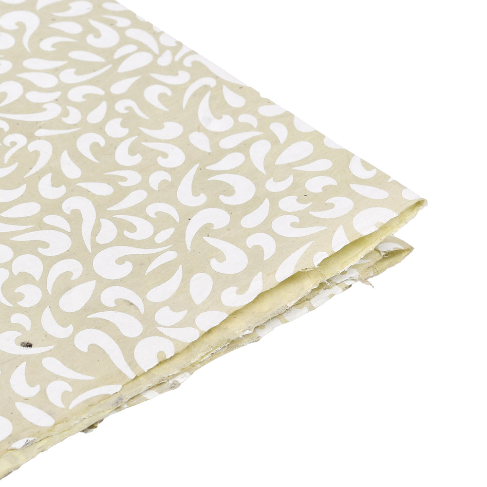 Eine Nahaufnahme von beigem Nepalpapier von ☆ mit weißem Paisleymuster und leicht ausgefransten Rändern - ideal für Buchbinden oder Geschenke Verpacken.