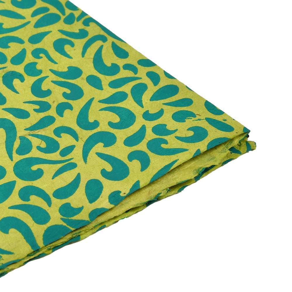 Gefalteter gelber Stoff mit grünen abstrakten Paisley-Mustern von ☆ auf weißem Hintergrund - perfekt für Geschenkverpackungen oder kreative Buchbindearbeiten.