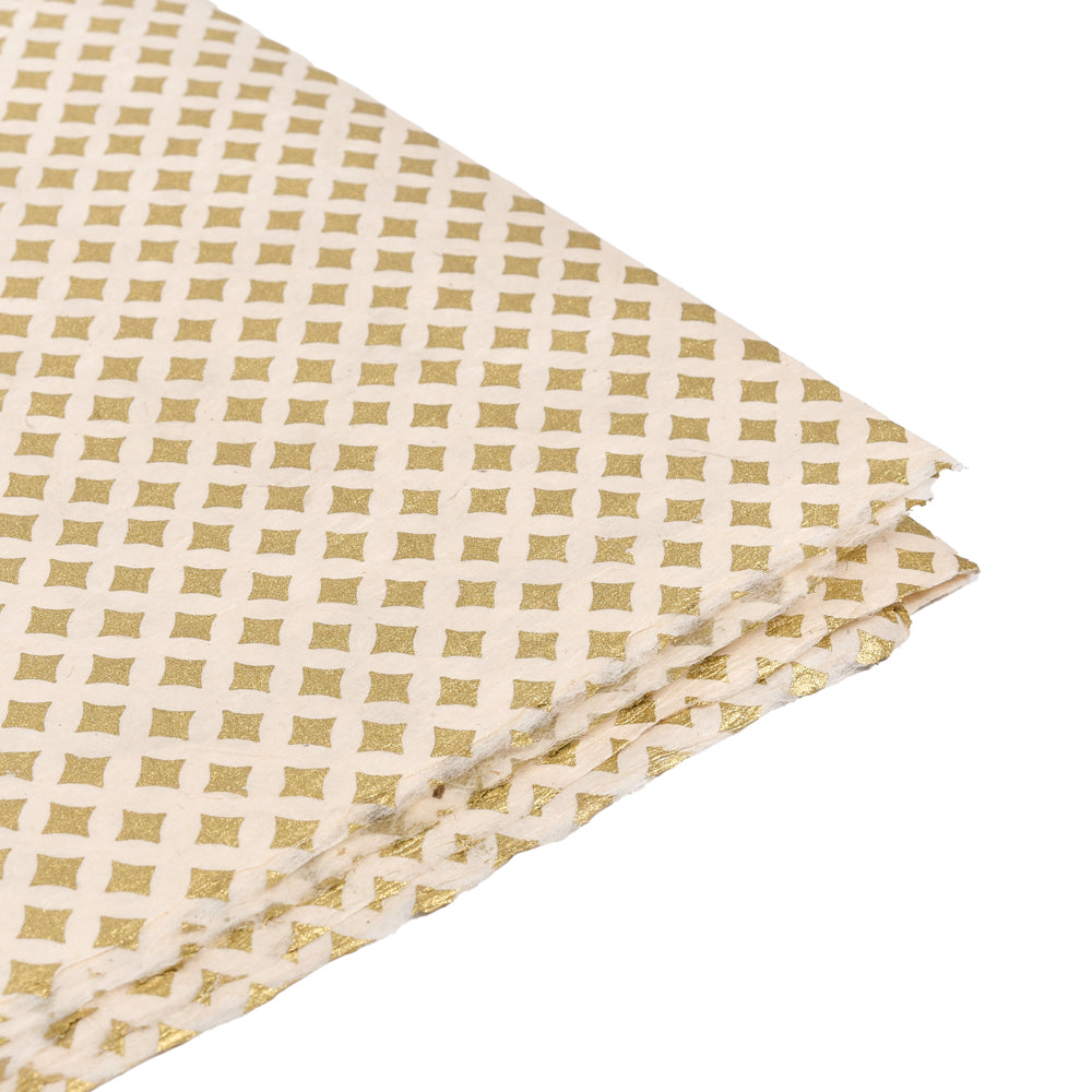 Gefaltetes cremefarbenes Nepalpapier mit einem goldenen geometrischen Quadratmuster, das sich ideal zum Verpacken von Geschenken oder zum Buchbinden eignet, auf weißem Hintergrund.