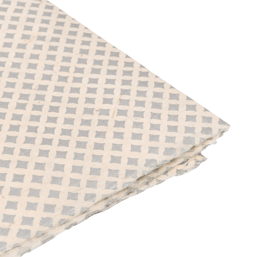 Ein Blatt ☆ strukturiertes weißes Nepalpapier mit einem sich wiederholenden grauen Rautenmuster, perfekt zum Buchbinden oder Verpacken von Geschenken, teilweise am Rand gefaltet.
