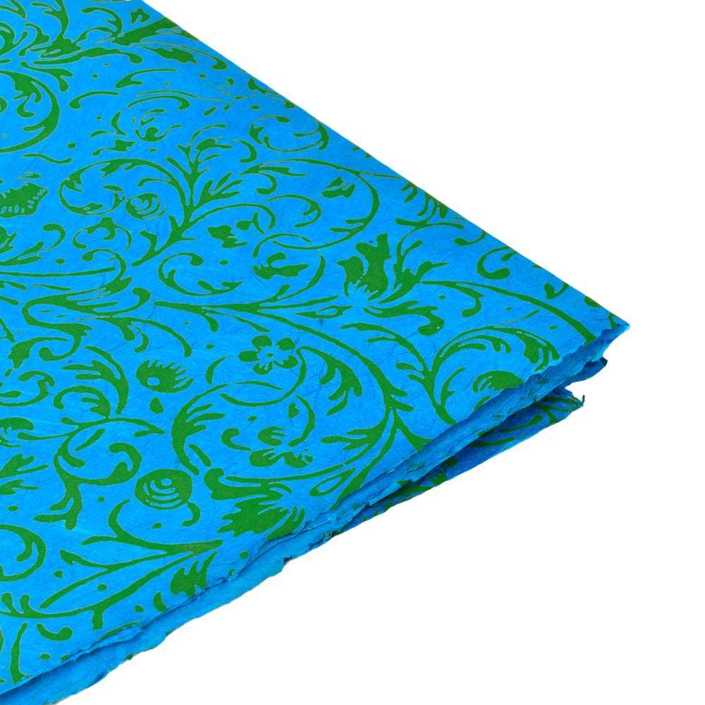 Blauer gefalteter Stoff mit grünen Blumen- und Rankenmotiven von ☆ auf weißem Hintergrund - perfekt für Geschenkverpackungen oder Buchbindungsideen, die von nepalesischem Papier inspiriert sind.