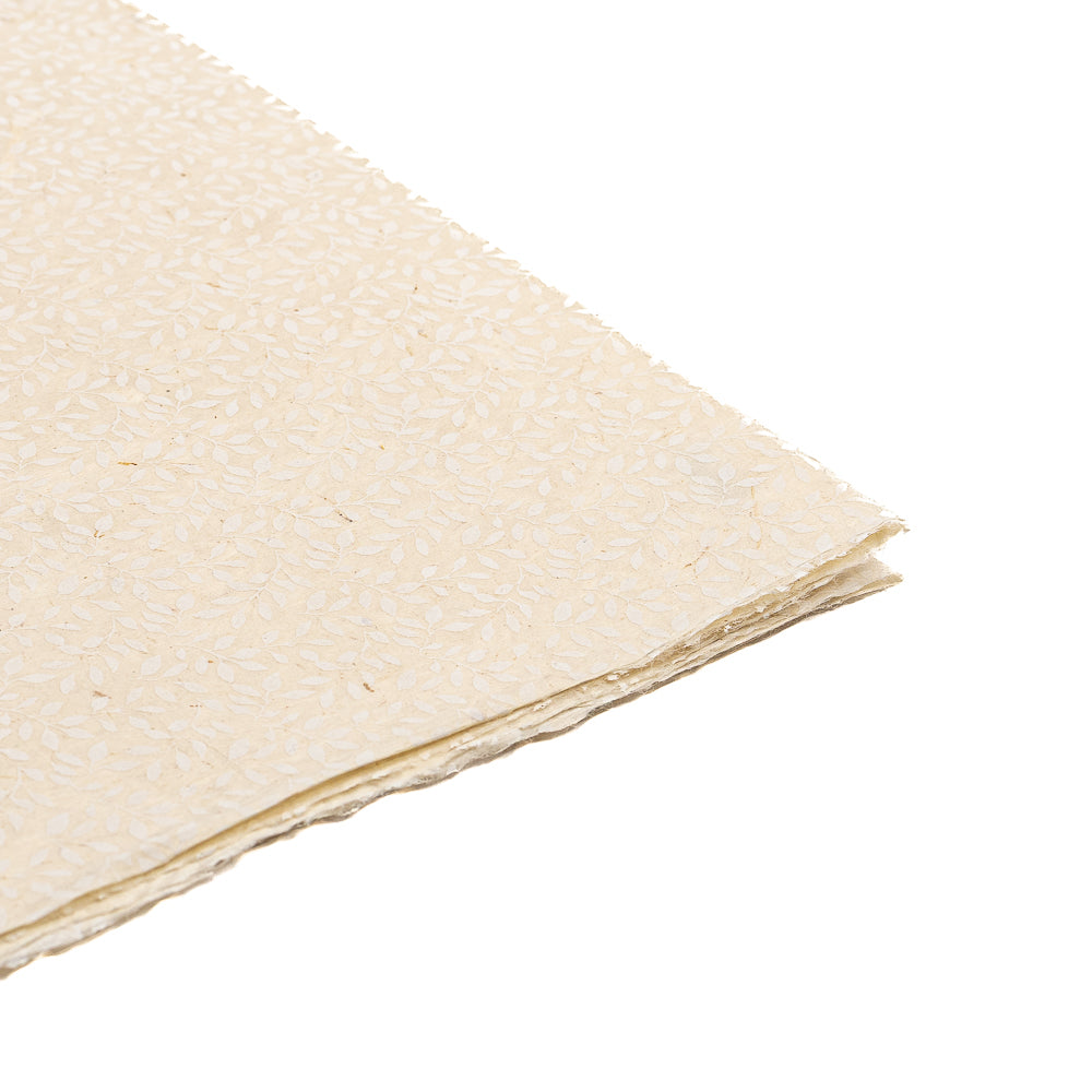 Ein Stapel cremefarbenes Nepalpapier von ☆ mit dezentem Blumenmuster auf weißem Hintergrund – ideal als nachhaltiges Papier für elegantes Geschenkpapier oder kreative Bastelprojekte.