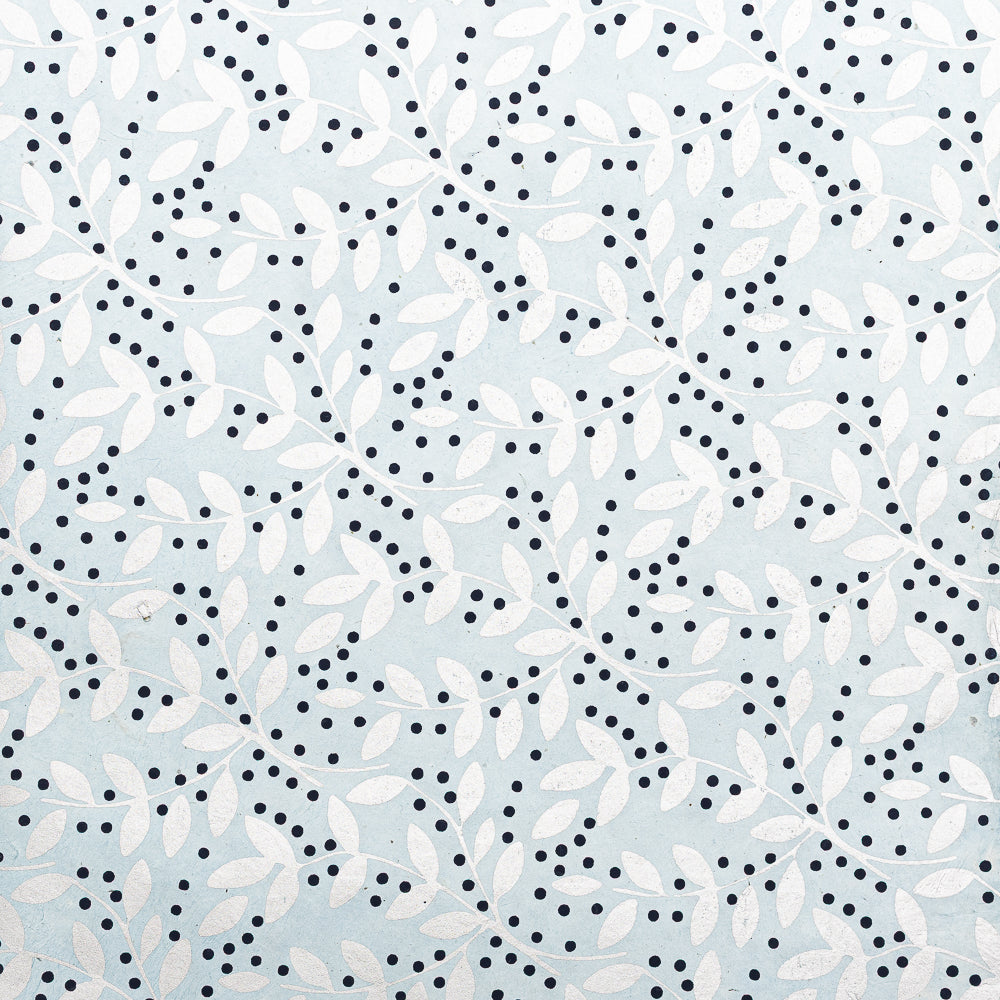 Weiße, blättrige Zweige mit kleinen schwarzen Punkten auf hellblauem Hintergrund bilden ein nahtloses, dekoratives Muster – ideal zum Verpacken von Geschenken mit nachhaltigem Nepalpapier von ☆.