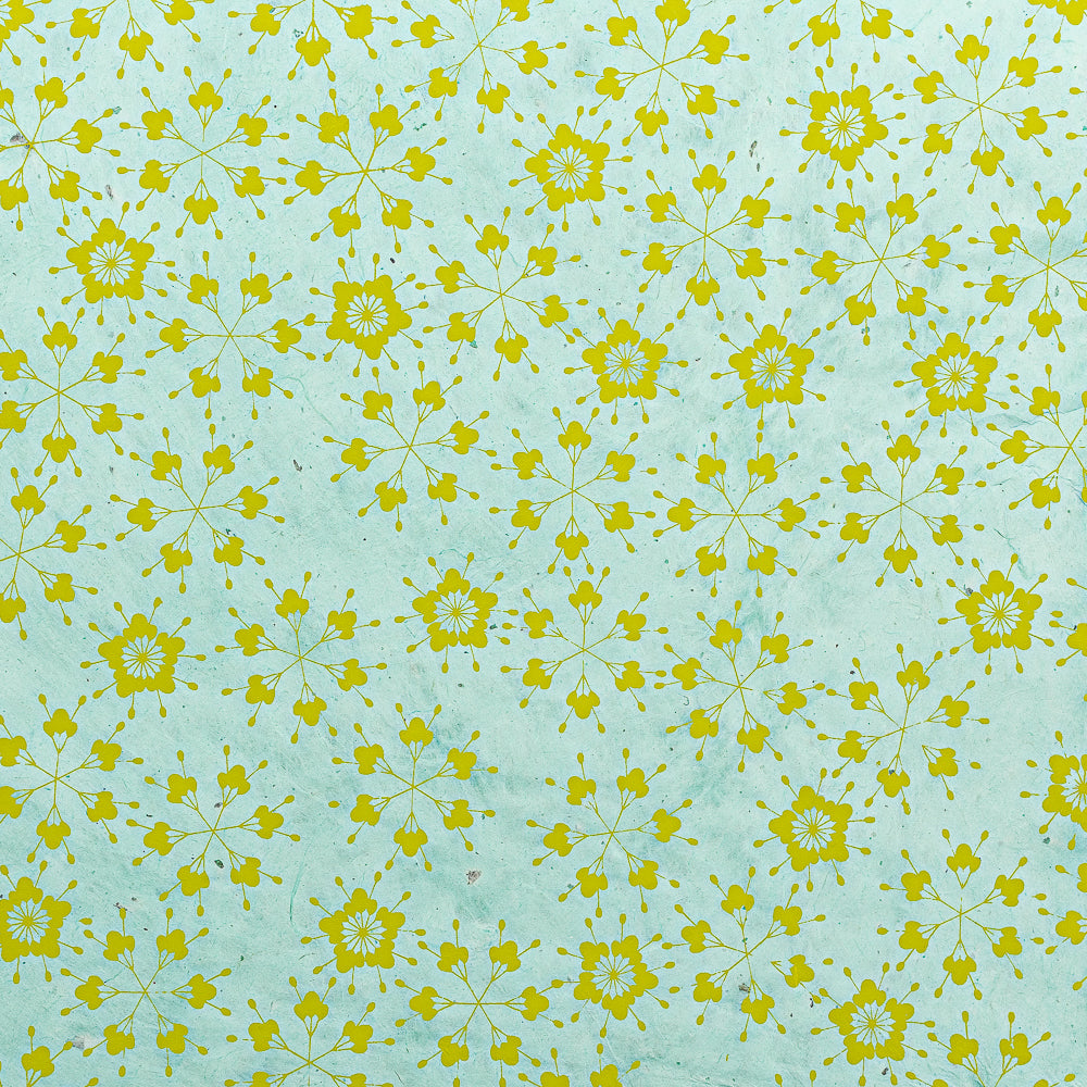 Ein gelbes, florales geometrisches Muster auf hellblauem Hintergrund bildet ein symmetrisches, sich wiederholendes Design – perfekt zum Verpacken von Geschenken mit nachhaltigem Papier wie Nepalpapier von ☆.