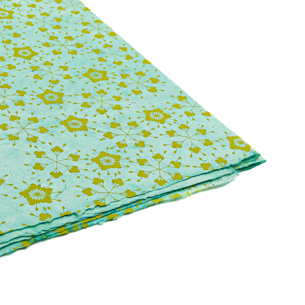 Gefalteter hellblauer Stoff mit gelbem Blumenmuster von ☆, präsentiert auf weißem Hintergrund – ideal als nachhaltiges Papier oder einzigartiges Geschenkpapier für jeden besonderen Anlass.