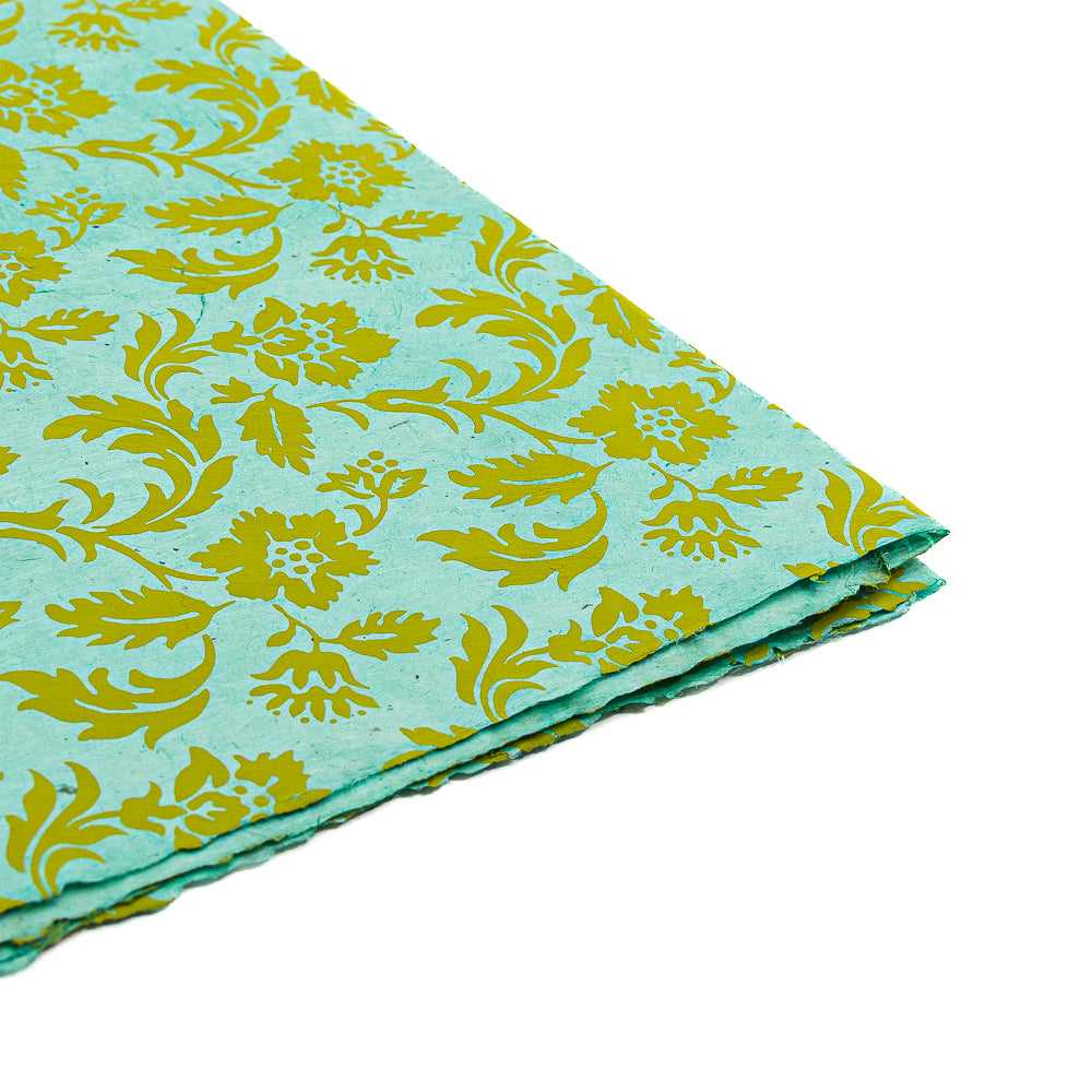 Gefaltetes aquablaues Geschenkpapier von ☆, hergestellt aus nachhaltigem Nepalpapier mit einem gelben Blumen- und Rankenmuster auf weißem Hintergrund.