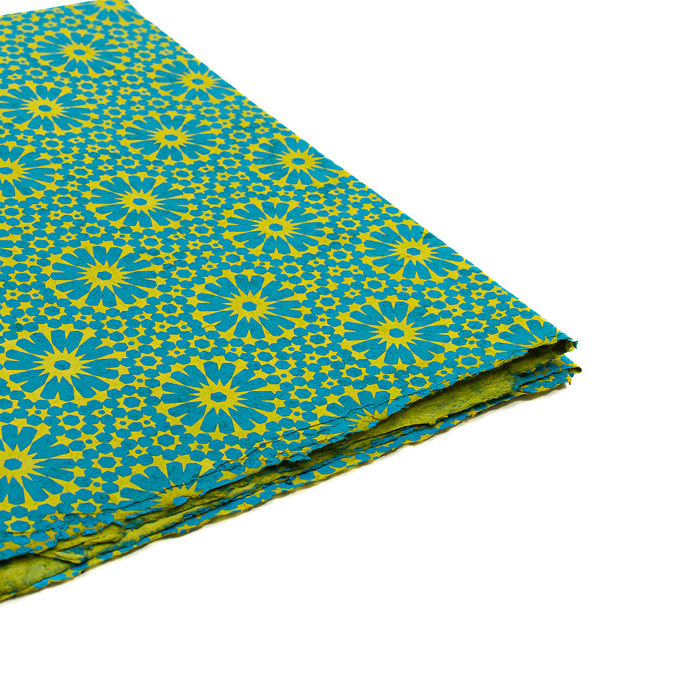 Gefalteter Stoff von ☆ mit einem gelb-blauen Blumen- und Sternenmuster auf weißem Hintergrund, inspiriert vom koreanischen Lotus – ideal als nachhaltiges Geschenkpapier oder für kreative Projekte.