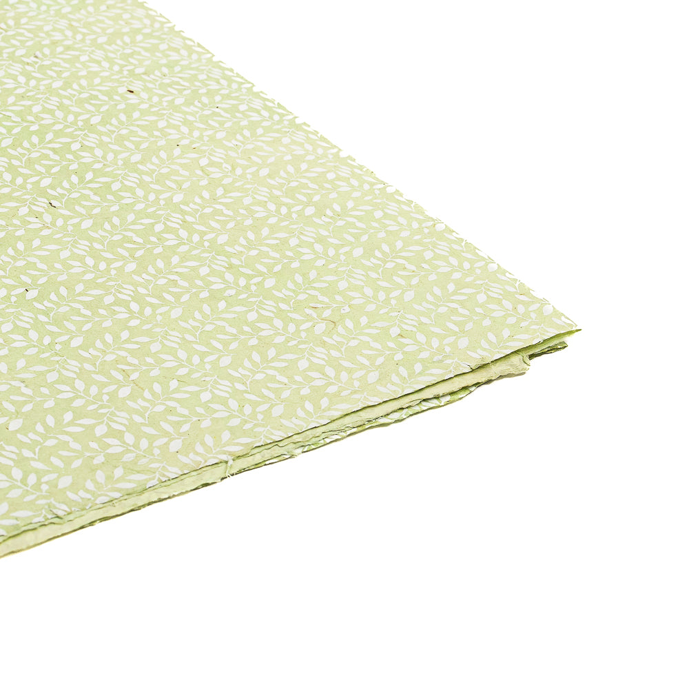 Ein ☆ Blatt hellgrünes Nepalpapier mit einem weißen Blattmuster auf einfarbigem Hintergrund – ideal für Geschenkverpackungen und alle, die auf der Suche nach nachhaltigem Papier sind.
