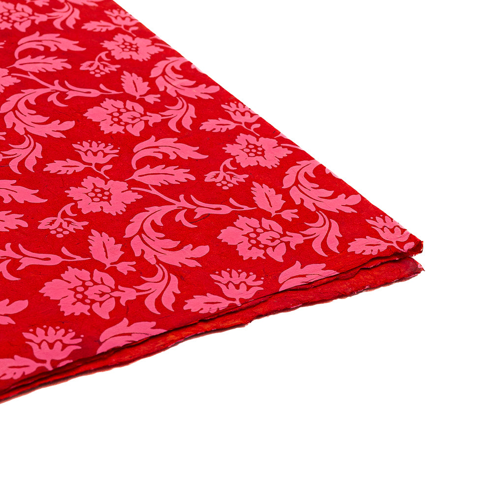 ☆ Rotes Nepalpapier mit einem rosa Blumen- und Blattmuster, gefaltet auf weißem Hintergrund – das ideale nachhaltige Geschenkpapier von ☆ für jeden besonderen Anlass.