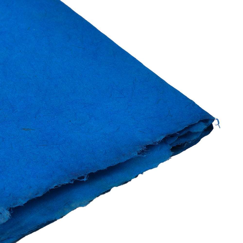Ein Blatt ☆ strukturiertes blaues Nepalpapier, ideal für Buchbinden, ist an einer Ecke auf weißem Hintergrund gefaltet.