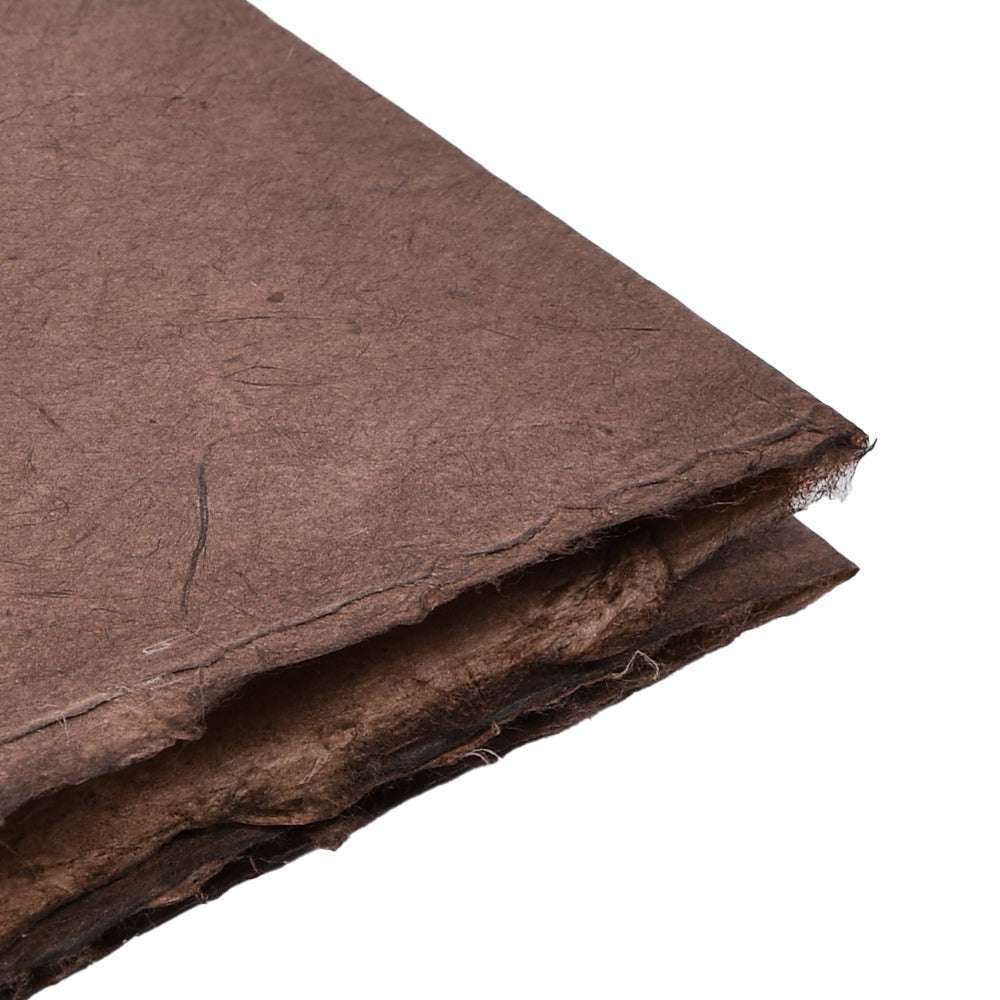 Eine Nahaufnahme von gestapelten braunen handgefertigten Papierbögen von ☆, auch Nepalpapier genannt, mit rauen, strukturierten Kanten - ideal zum Verpacken von Geschenken mit natürlichem Flair.