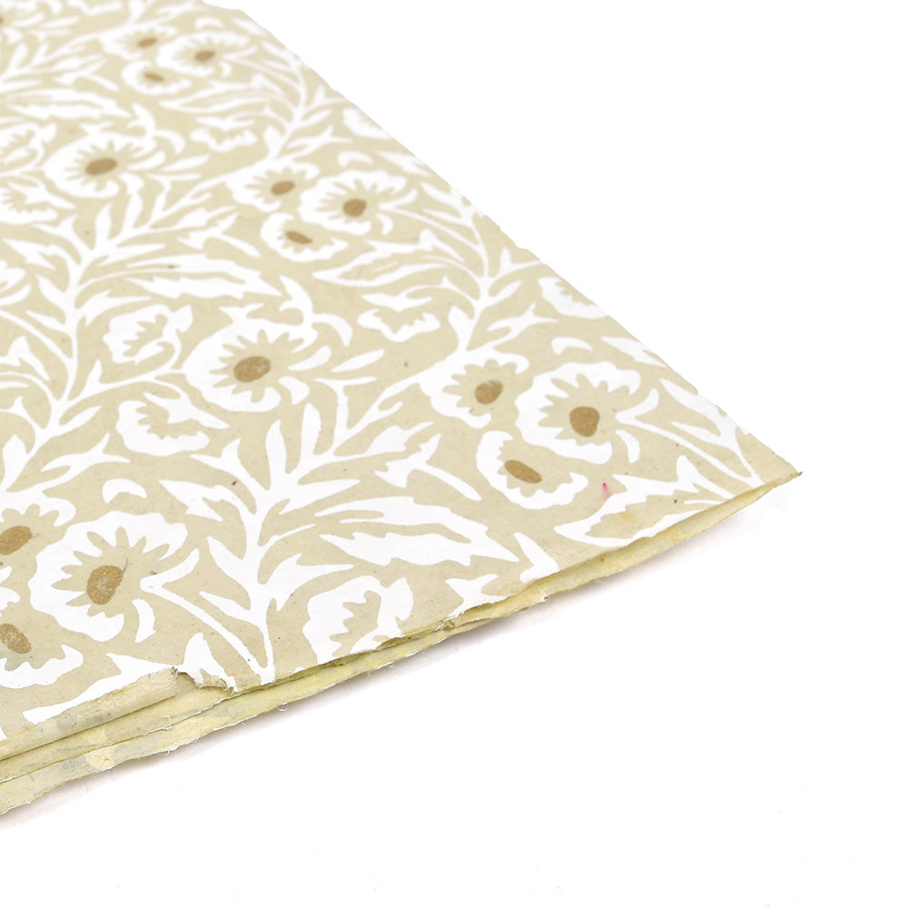 Cremefarbenes Nepalpapier von ☆ mit weißem Blumen- und Blattmuster, ideal zum Buchbinden oder Verpacken von Geschenken. Abgebildet in einem Winkel auf weißem Hintergrund.