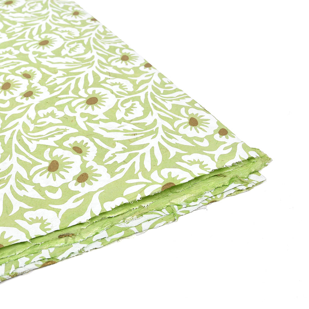 Grünes und weißes Nepalpapier mit Blumenmuster, handgefertigt, mit rauen, strukturierten Rändern, ideal zum Einpacken von Geschenken oder zum Buchbinden, schräg gelegt.