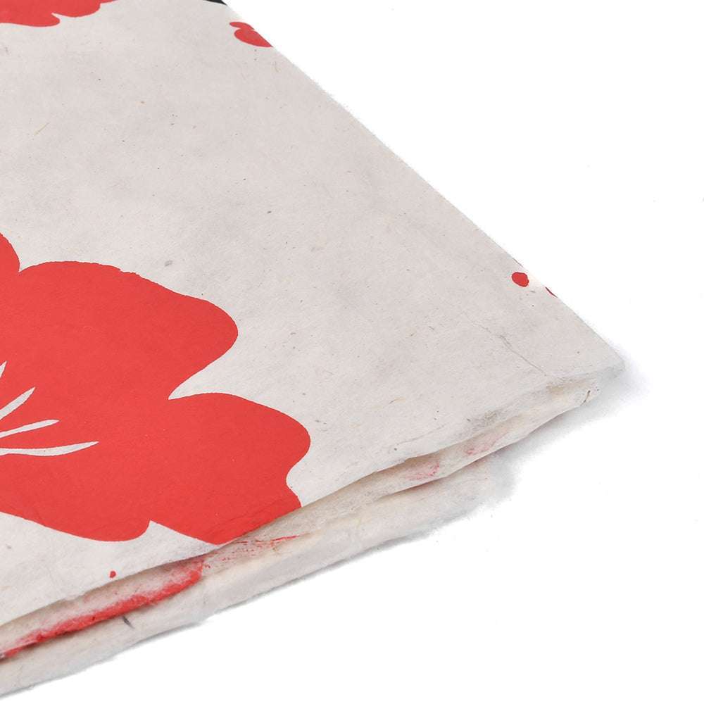 Nahaufnahme des gefalteten weißen Stoffes von ☆ mit einem leuchtend roten Blumendruck auf weißem Hintergrund - ideal für Geschenkverpackungen oder kreative Buchbinden-Projekte.