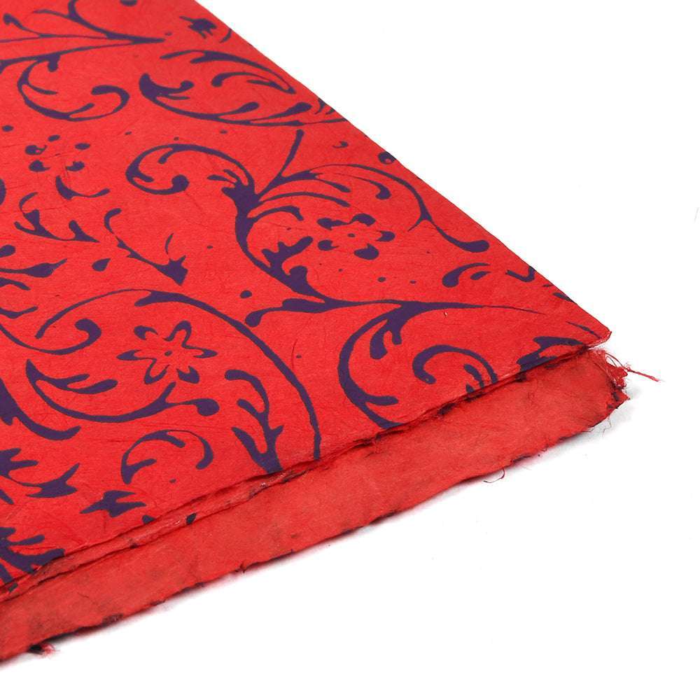 ☆ Handgefertigtes rotes Nepalpapier mit dunkelblauen Blumenmustern und rauen, strukturierten Rändern, ideal zum Einpacken von Geschenken oder zum Buchbinden; auf weißem Hintergrund.