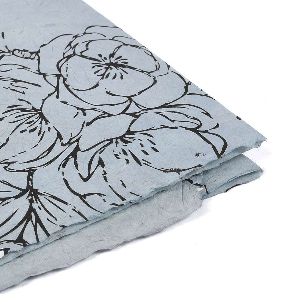 Zwei strukturierte, hellblaue Nepalpapierbögen von ☆ mit schwarzem Blumenmuster auf der Oberseite - ideal zum Verpacken von Geschenken oder um Ihrem nächsten Buchbindeprojekt einen Hauch von Eleganz zu verleihen.