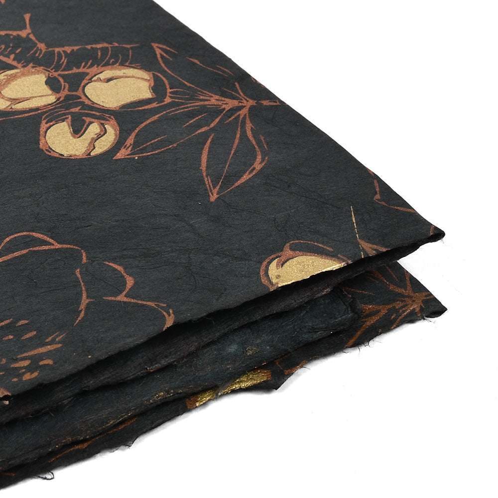 Stapel schwarzes Nepalpapier von ☆ mit goldenen und braunen Blumen- und Fruchtmustern, ideal zum Buchbinden oder Verpacken von Geschenken, auf weißem Hintergrund.