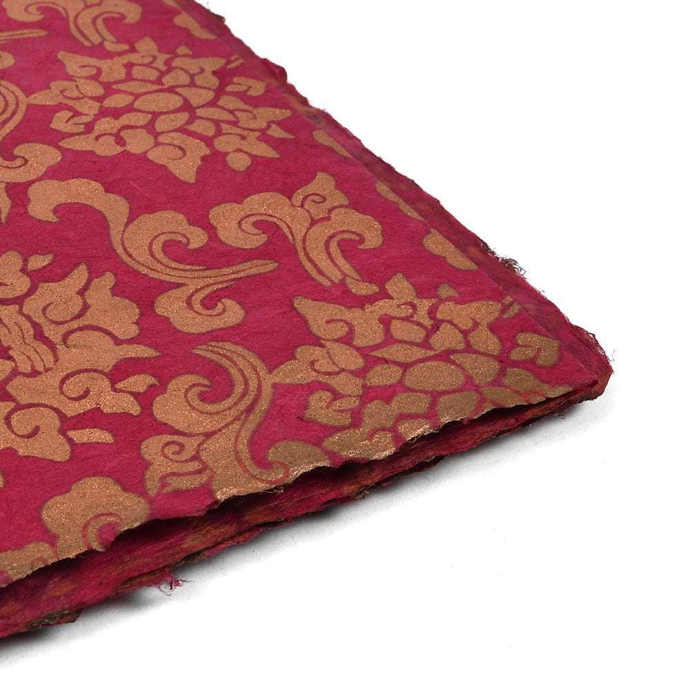Rotes handgeschöpftes Nepalpapier mit goldenen Blumenmustern, schräg gestellt und mit strukturierten Rändern - perfekt für Geschenkverpackungen oder Bastelprojekte.