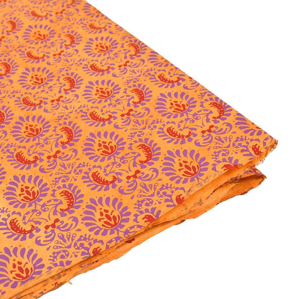 Orangefarbenes, handgefertigtes Nepalpapier mit lila und rotem Blumenmuster, von der Seite betrachtet - ideal zum Verpacken von Geschenken oder zum Buchbinden.
