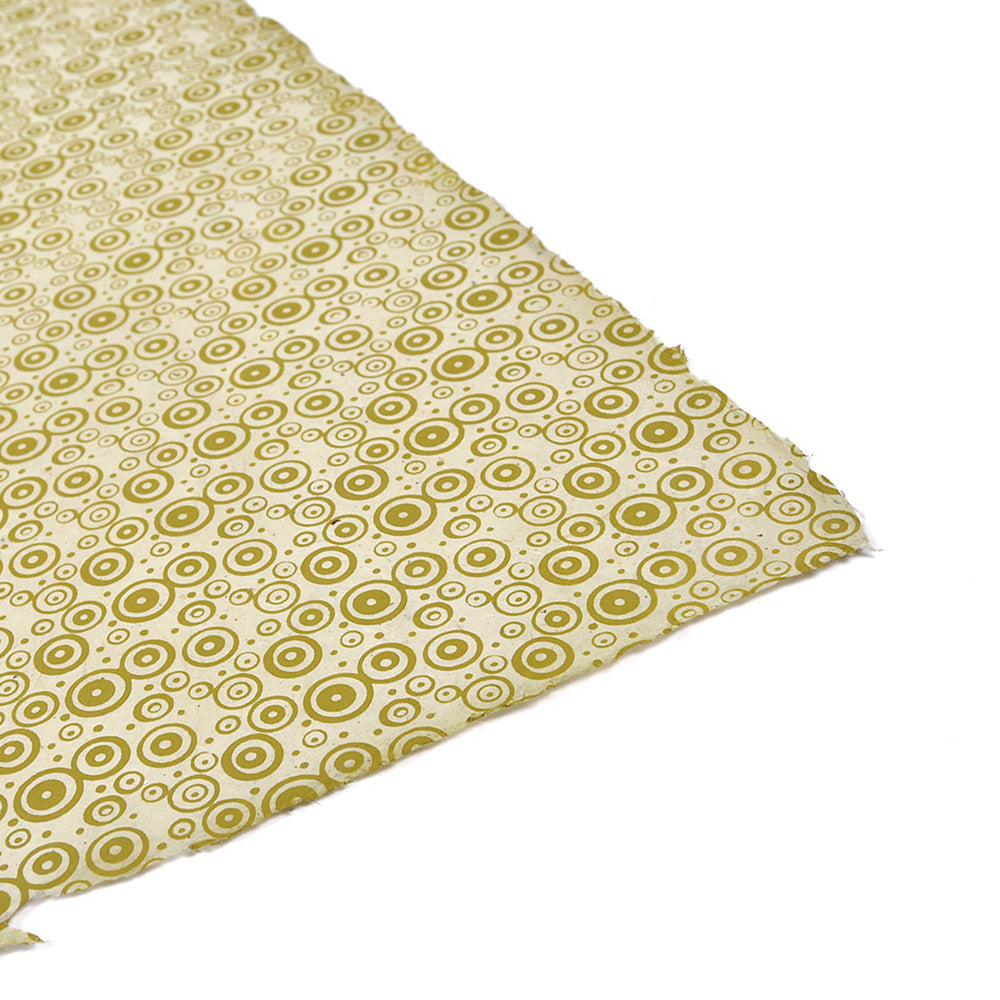 Ein Stück gelbes Nepalpapier von ☆ mit grünen konzentrischen Kreisen auf weißem Hintergrund - ideal für Buchbinden oder einzigartige Geschenke verpacken.