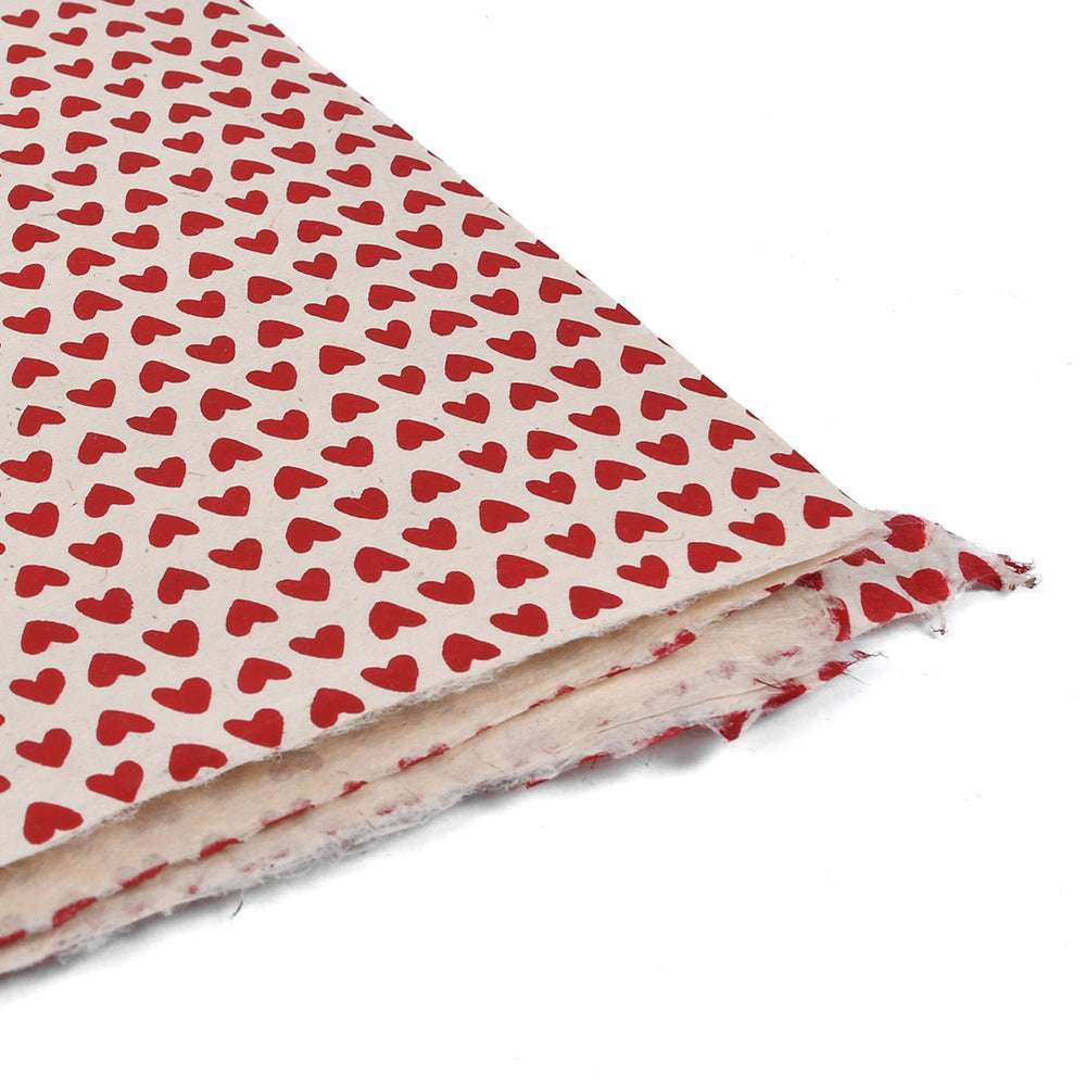 Ein Blatt ☆ Nepalpapier mit kleinen roten Herzen auf weißem Hintergrund und leicht eingerissenen Rändern - perfekt zum Buchbinden oder Verpacken von Geschenken.