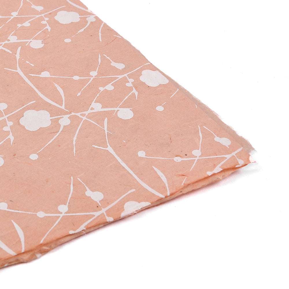 ☆ Pfirsichfarbenes Nepalpapier mit weißem Blumen- und Zweigmuster, schräggestellt auf weißem Hintergrund - perfekt als handgeschöpftes Papier für Geschenkverpackungen.