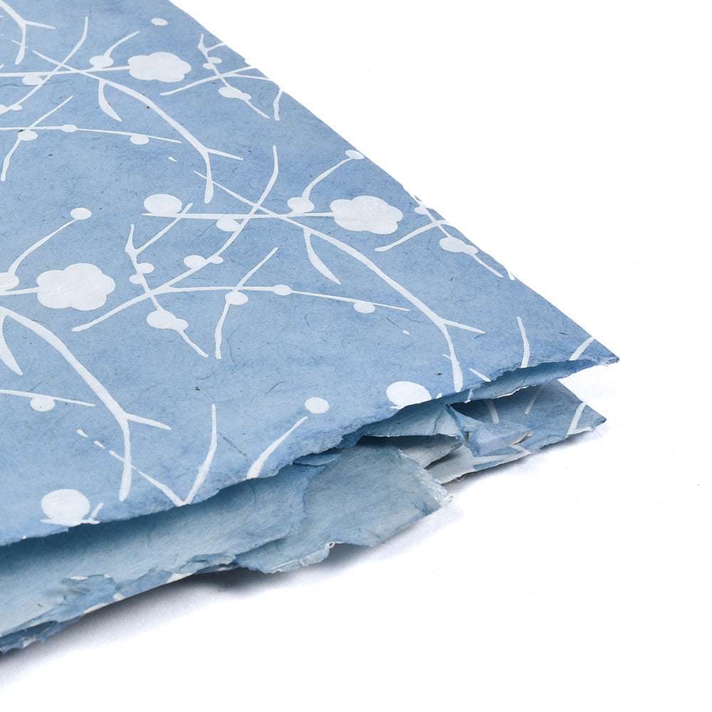 Blaues dekoratives Nepalpapier mit weißem Blumen- und Zweigmuster, ideal zum Verpacken von Geschenken oder zum Buchbinden, auf weißem Hintergrund.