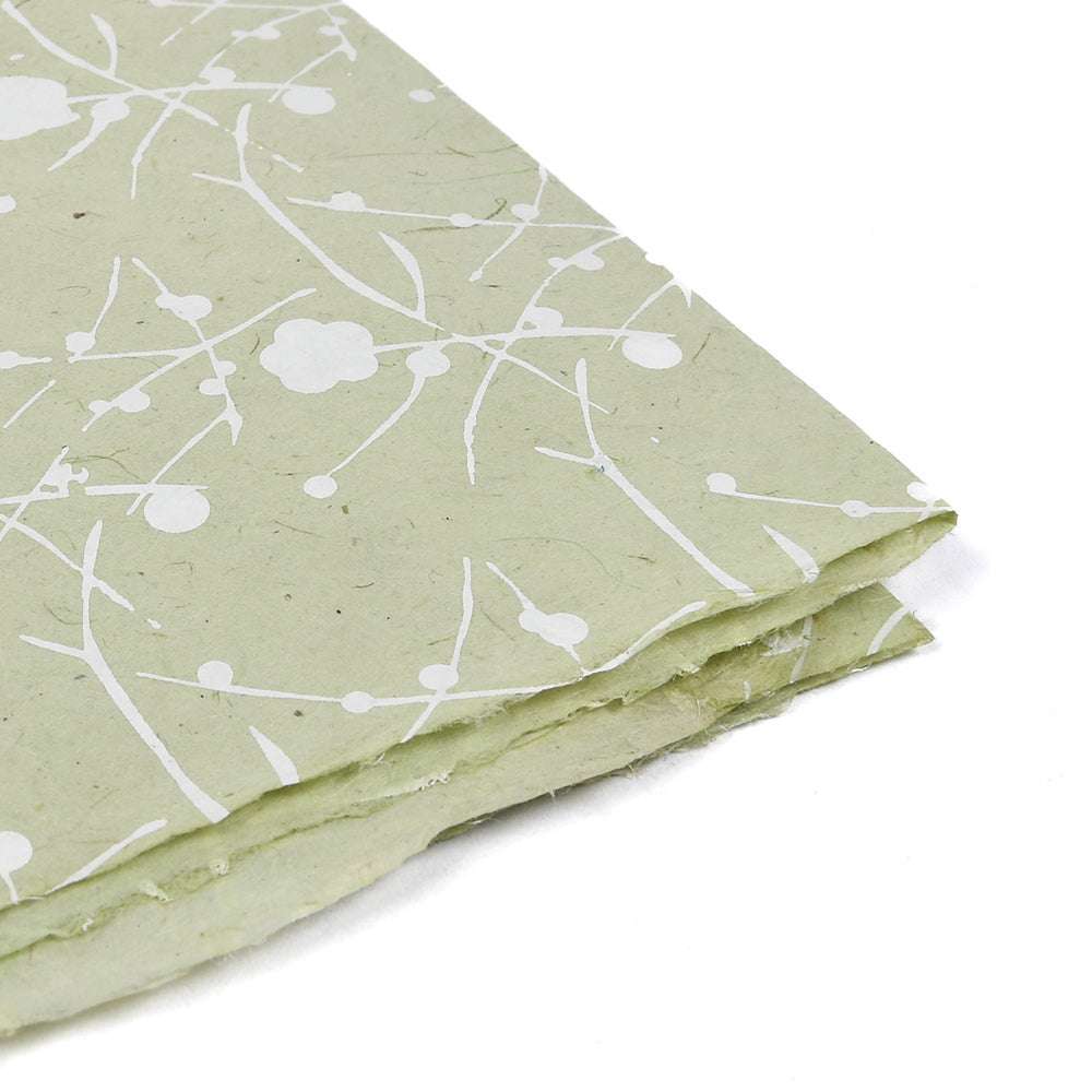 Hellgrünes Nepalpapier von ☆, mit weißem Blumen- und Zweigmuster, ideal für Buchbinden oder Geschenke Verpacken, in der Ecke des Bildes gestapelt.