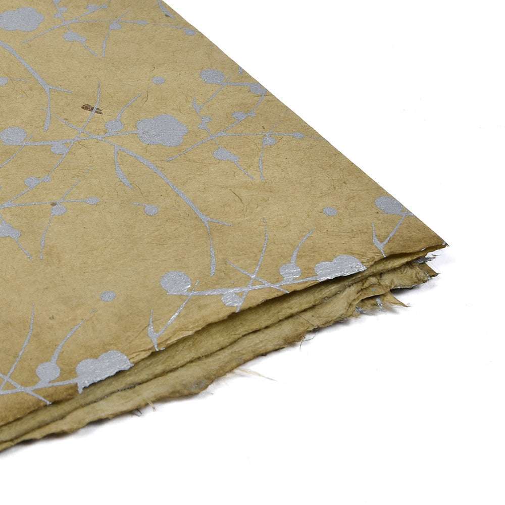 Ein ☆ Blatt strukturiertes Nepalpapier mit silbernen Blumenakzenten an einer Ecke und leicht ausgefransten Kanten - ideal für Geschenkverpackungen oder Buchbinden.