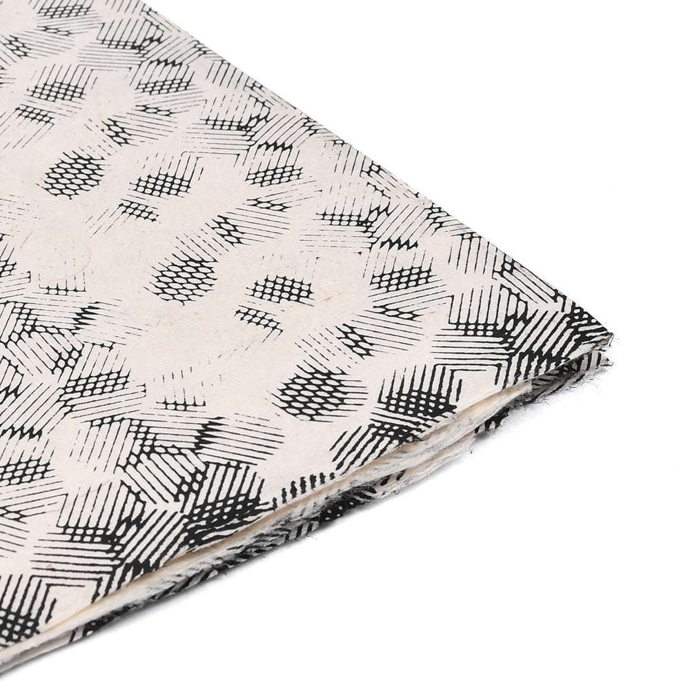 Ein gefalteter Bogen ☆ Nepalpapier mit schwarzen geometrischen Mustern auf Weiß - ideal für Geschenkverpackungen oder Buchbindearbeiten.