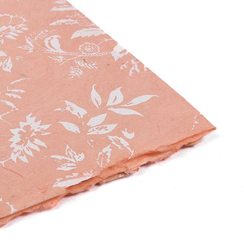 Pfirsichfarbenes handgefertigtes Nepalpapier von ☆ mit weißen Blumenmustern, ideal zum Verpacken von Geschenken oder zum Einbinden von Büchern, abgebildet in einem Winkel auf weißem Hintergrund.