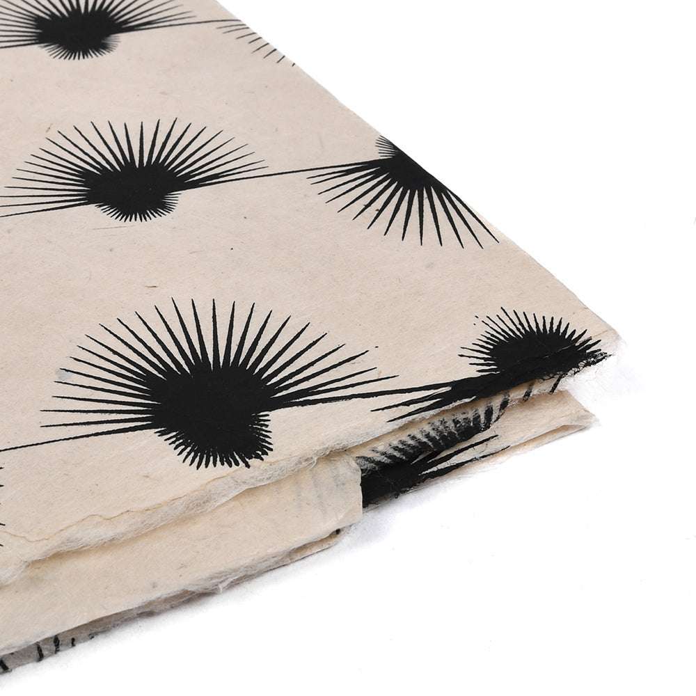 Das handgefertigte beigefarbene Nepalpapier hat ein sich wiederholendes schwarzes Sternenmuster und gestapelte, leicht überlappende Ränder - ideal für Buchbinden oder stilvolle Geschenkverpackungen.