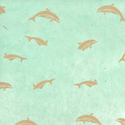 Muster von hellbraunen Delfinen, die auf einem strukturierten, hellgrünen Hintergrund schwimmen von ☆, ideal für Geschenke Verpacken oder kreative Buchbinden-Projekte mit einzigartigem Nepalpapiere-Flair.