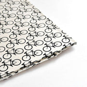 Nahaufnahme von ☆ Nepalpapieren mit einem sich wiederholenden schwarzen Fahrradmuster auf Weiß - ideal für Buchbinden oder stilvolle Geschenkverpackungen.