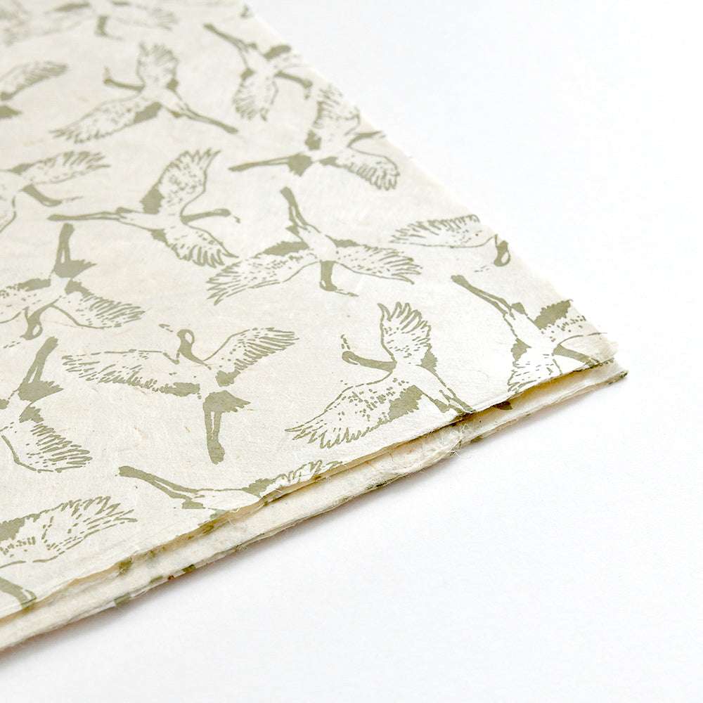 Cremefarbene Nepalpapiere von ☆ mit einem sich wiederholenden Kranichmuster in hellgrüner Tinte, gefaltete Kanten - ideal für Geschenkverpackungen oder Buchbindearbeiten.