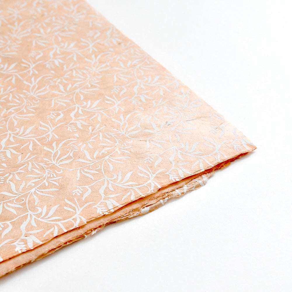 ☆ Pfirsichfarbene gemusterte Nepalpapiere mit weißem Blattmuster, ideal für Buchbinden oder Geschenkverpackungen, abgebildet auf weißem Hintergrund.