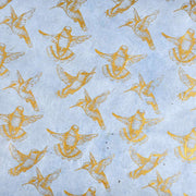 Goldfarbene Kolibriillustrationen auf hellblauem Hintergrund, gleichmäßig verteilt in einem sich wiederholenden Muster - perfekt für Buchbinden oder elegante Geschenkverpackungen in Nepalpapieren ☆.