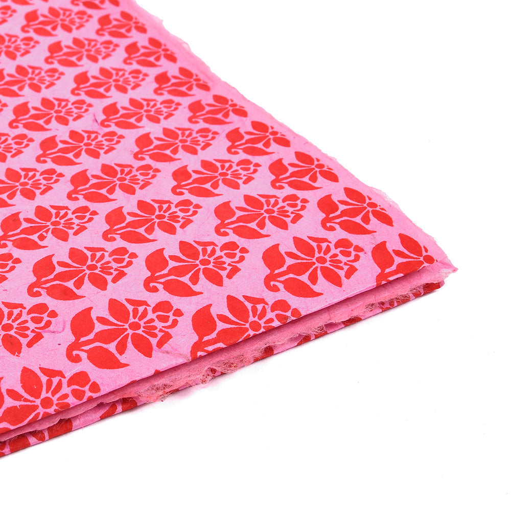 Rosa Nepalpapier mit einem sich wiederholenden roten Blumenmuster, sauber gefaltet auf weißem Papier - ideal zum Verpacken von Geschenken oder zum Buchbinden.