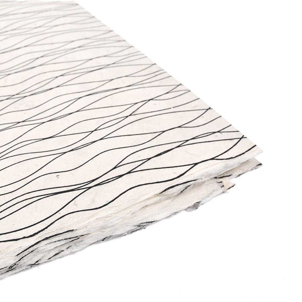 Eine Seitenansicht von gestapelten, cremefarbenen Nepalpapierbögen mit schwarzen Wellenlinien von ☆-ideal für Bucheinbände oder einzigartige Geschenkverpackungen.