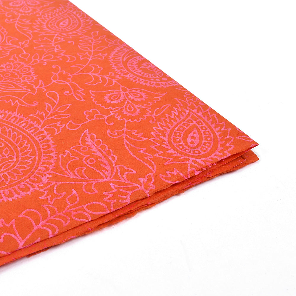Gefaltetes Stück orangefarbenes Nepalpapier von ☆ mit rosa Blumen- und Paisleymuster auf Weiß - ideal für Buchbinden oder Geschenke Verpacken.