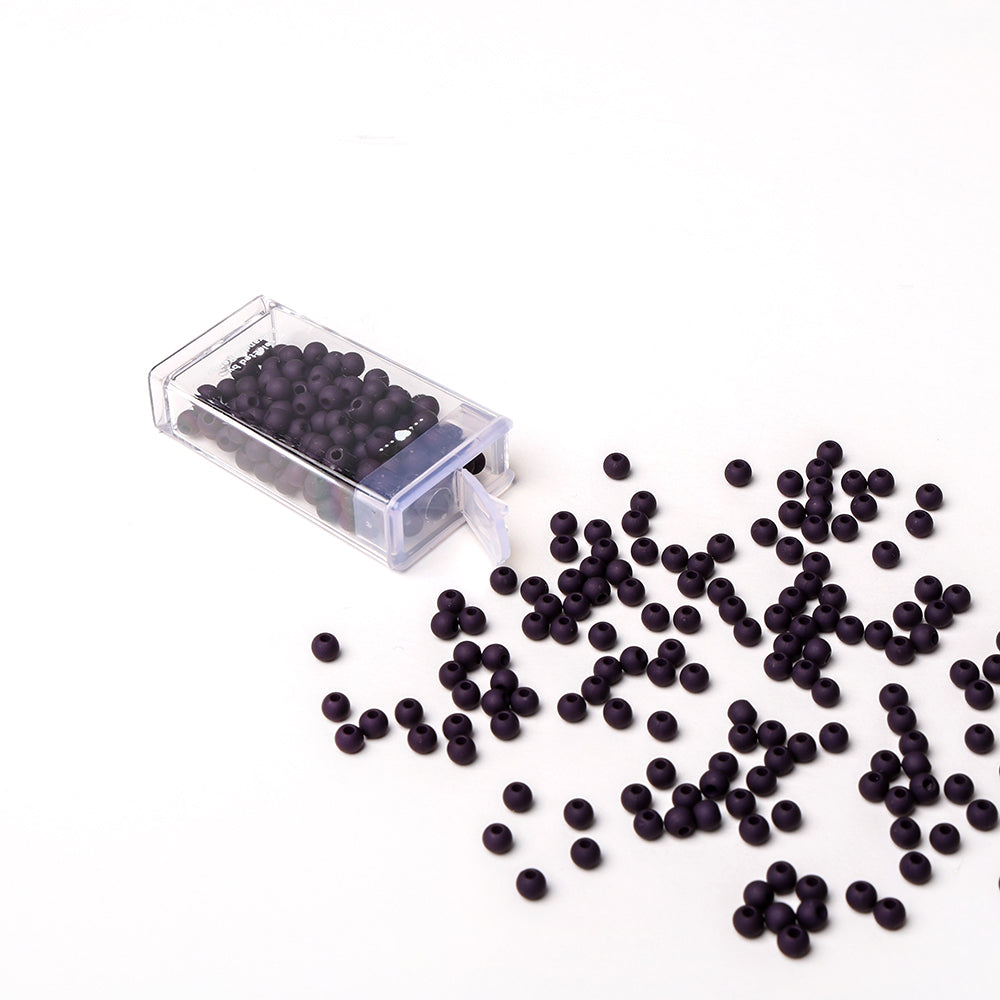 Alexandra Renke Acrylperlen auf einer weißen Fläche verstreut, einige davon aus einem durchsichtigen Behälter verschüttet - ideal für Bastelprojekte oder Schmuck basteln.