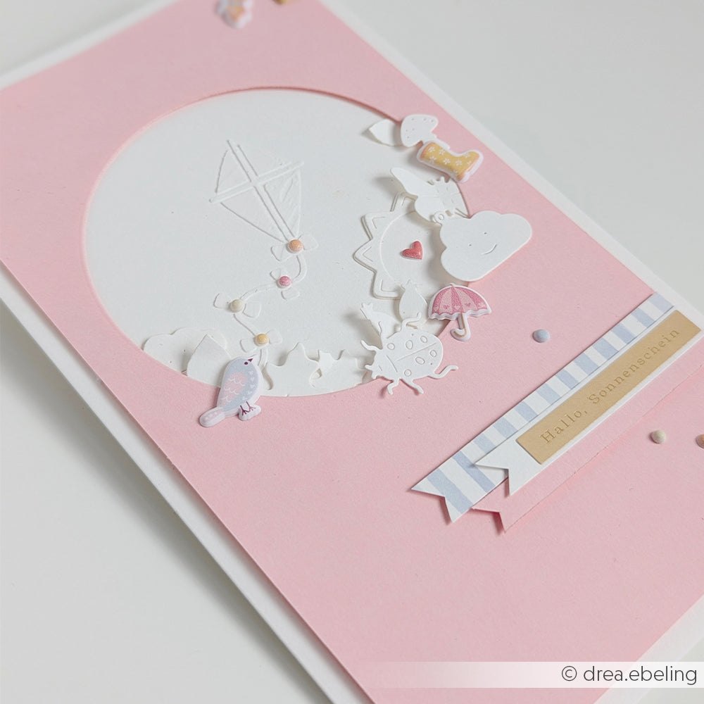 Rosa Karte mit weißen und pastellfarbenen Motiven, darunter Wolken, ein Vogel und ein Aufkleber mit der Aufschrift „Hallo, Sonnenschein“. Perfekt für kreative Projekte oder als bezaubernder Aufkleber, der deiner Sammlung eine fröhliche Note verleiht.