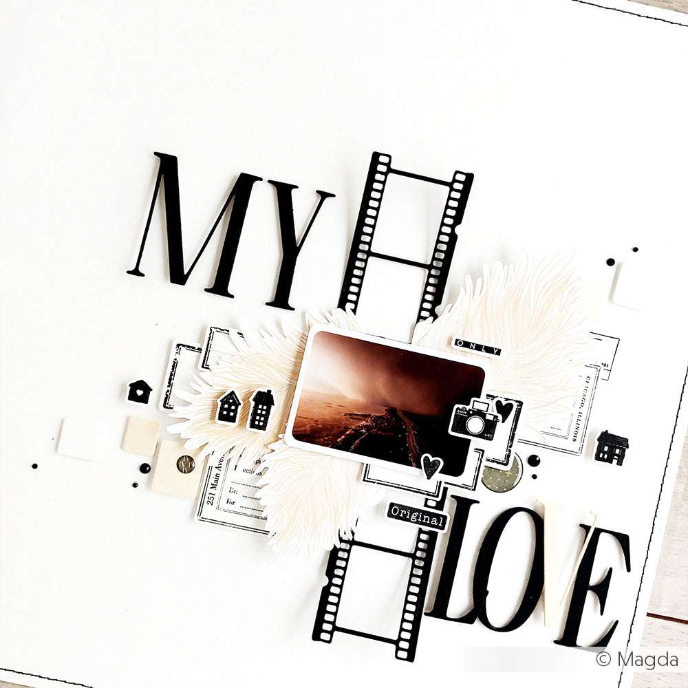 Eine Scrapbook-Seite mit dem Text "MY LOVE", Filmstreifen, die mit Alexandra Renkes Motivstanze Analog Film Rahmen gemacht wurden, Federn, kleinen Häusern und einem Straßenfoto bei Sonnenuntergang.