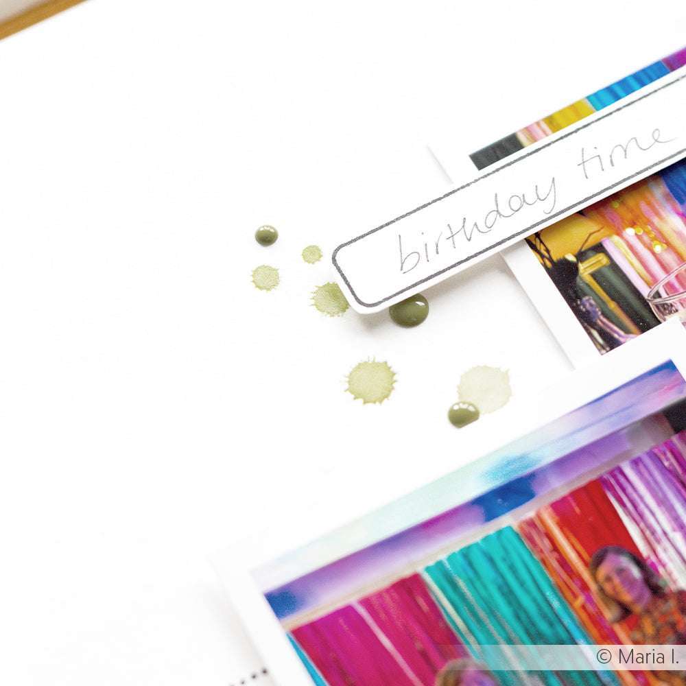 Nahaufnahme einer Scrapbook-Seite mit Fotos, Luftschlangen, Farbspritzern und einem "Birthday Time"-Etikett, dekoriert mit Alexandra Renke Rub-On Motiven für einzigartige Effekte.